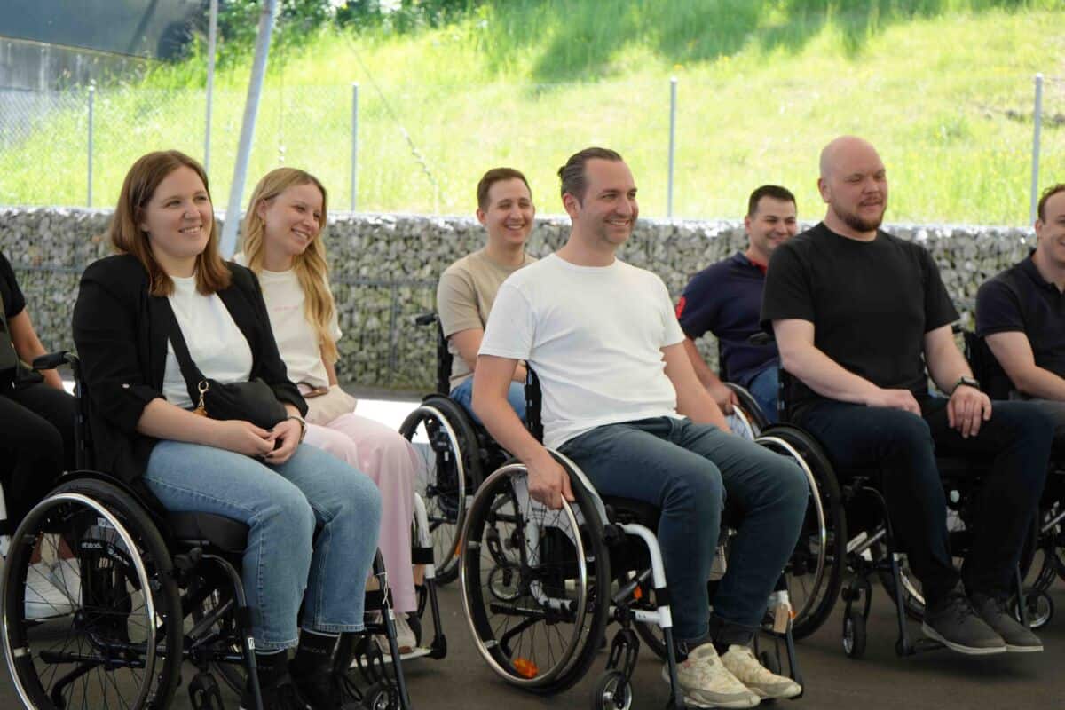 Gruppenfoto indem Mitarbeiter im Rollstuhl sitzen.